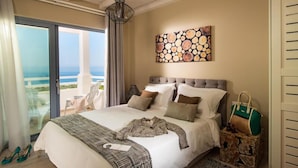 A bedroom with a large bed, a view of the ocean, a ceiling light, and a painting on the wall. - Villas Crete (Hersonissos)