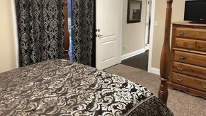 A bedroom with a bed, a dresser, a television, and a door leading to another room. - H-DERBY, Keeneland, Bourbon or Family Gathering!  (Frankfort)