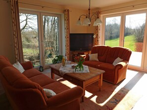 A living room with a sofa, a coffee table, and a television. - Apartments Schleibach - Apartments Hartmann (Rabenkirchen-Faulück)