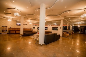 A spacious lobby with a high ceiling, modern lighting fixtures, and a central column. - Royal Reach Family Resort (Udawalawa)