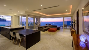 Um espaço moderno com cozinha, área de estar com vista para o mar e sala de jantar.