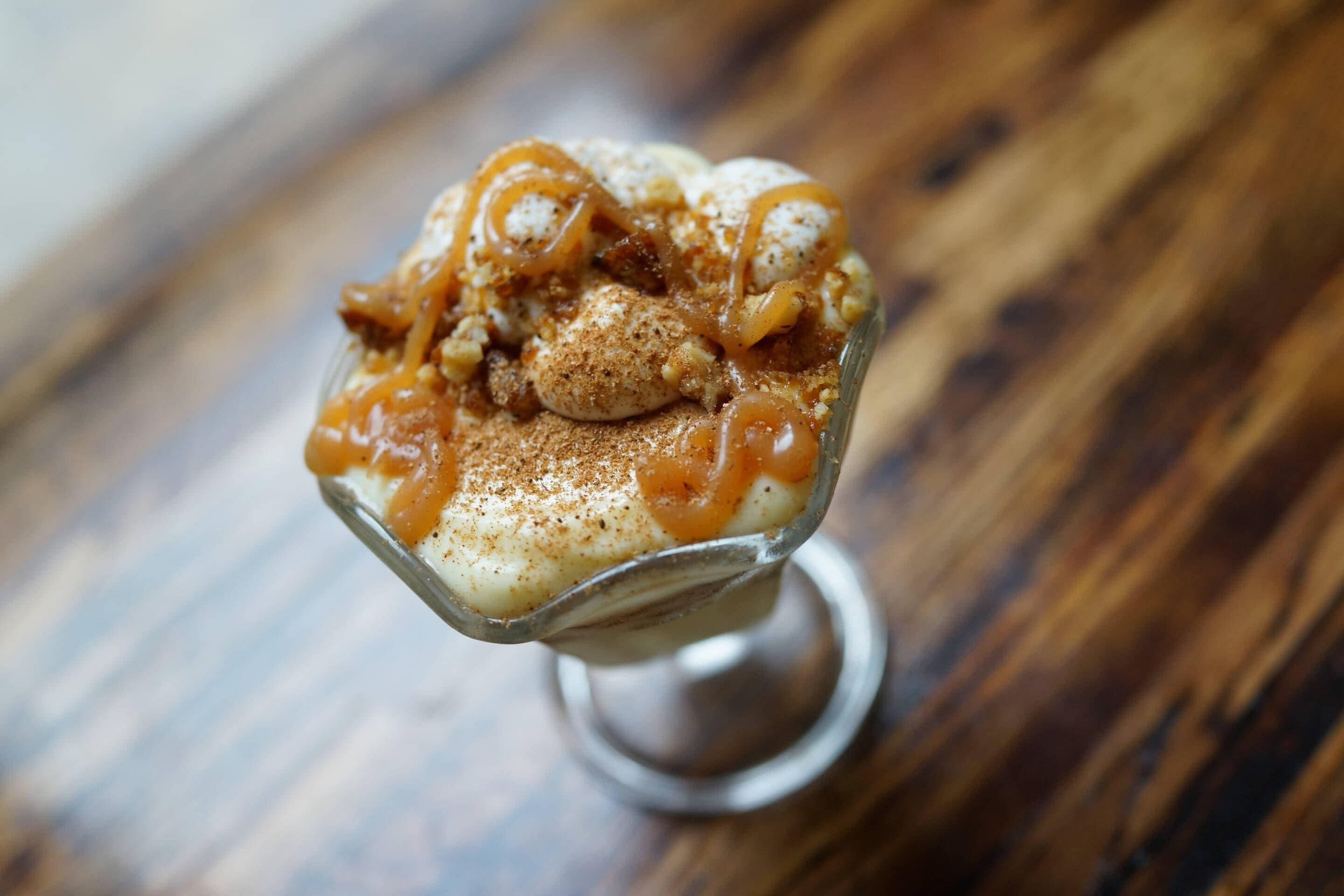 Un postre en un recipiente de vidrio sobre una mesa de madera.