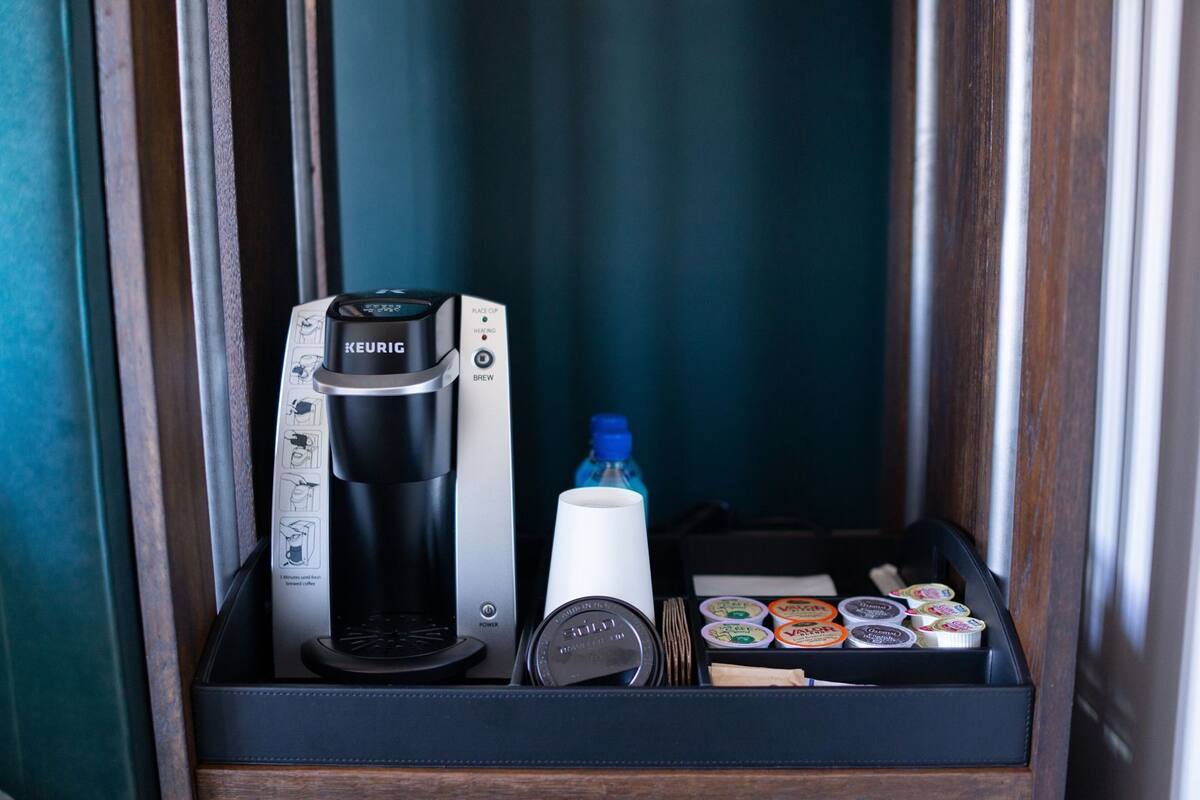 A minibar with a Keurig coffee maker, a water bottle, and assorted coffee pods.