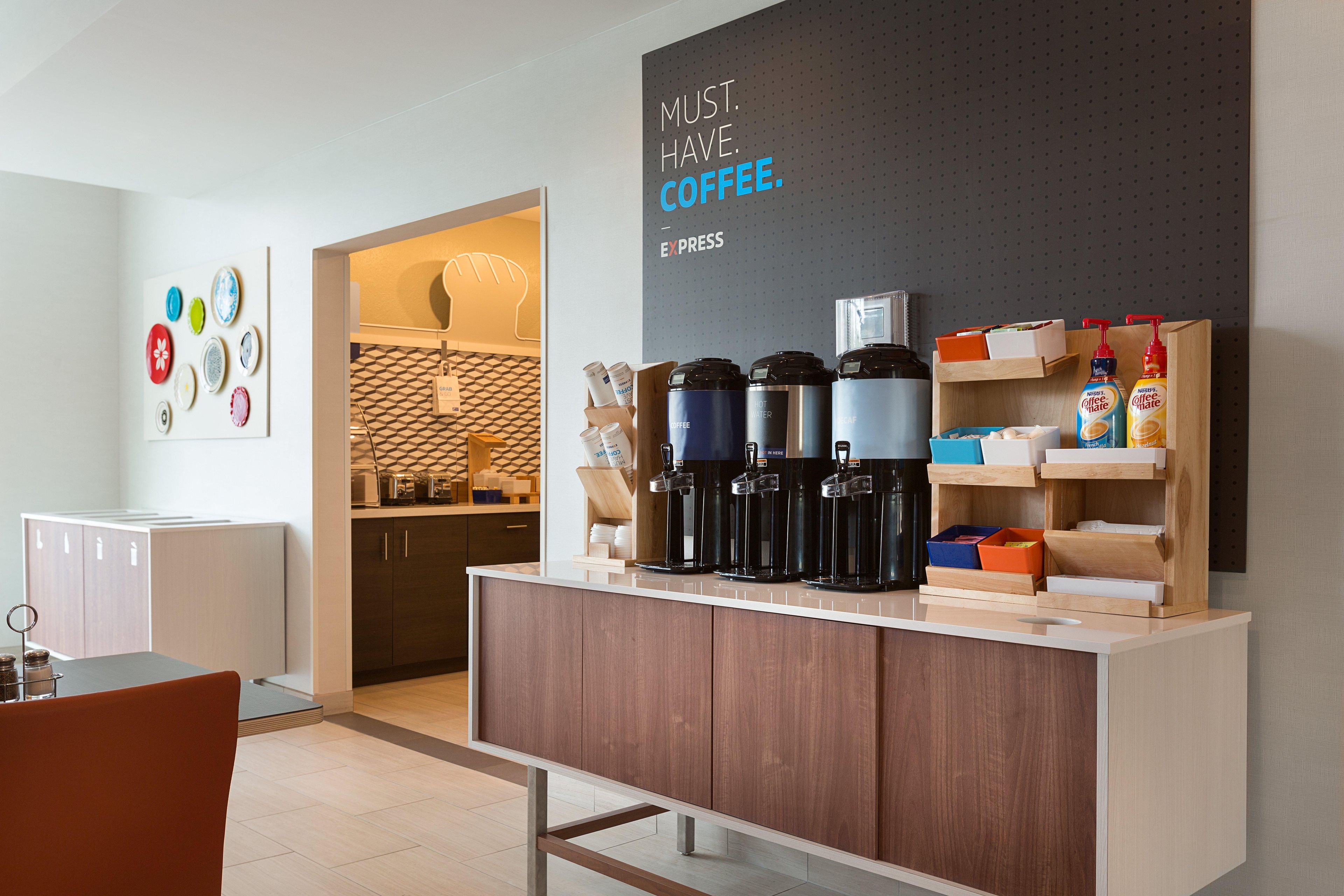 Uma cozinha moderna com um espaço para café, com várias cafeteiras e um aviso que diz "PRECISA. DE. CAFÉ".