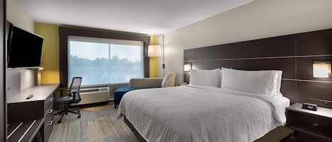 Une chambre d’hôtel avec un grand lit, un bureau, une chaise, une télévision et une fenêtre donnant sur un beau paysage.