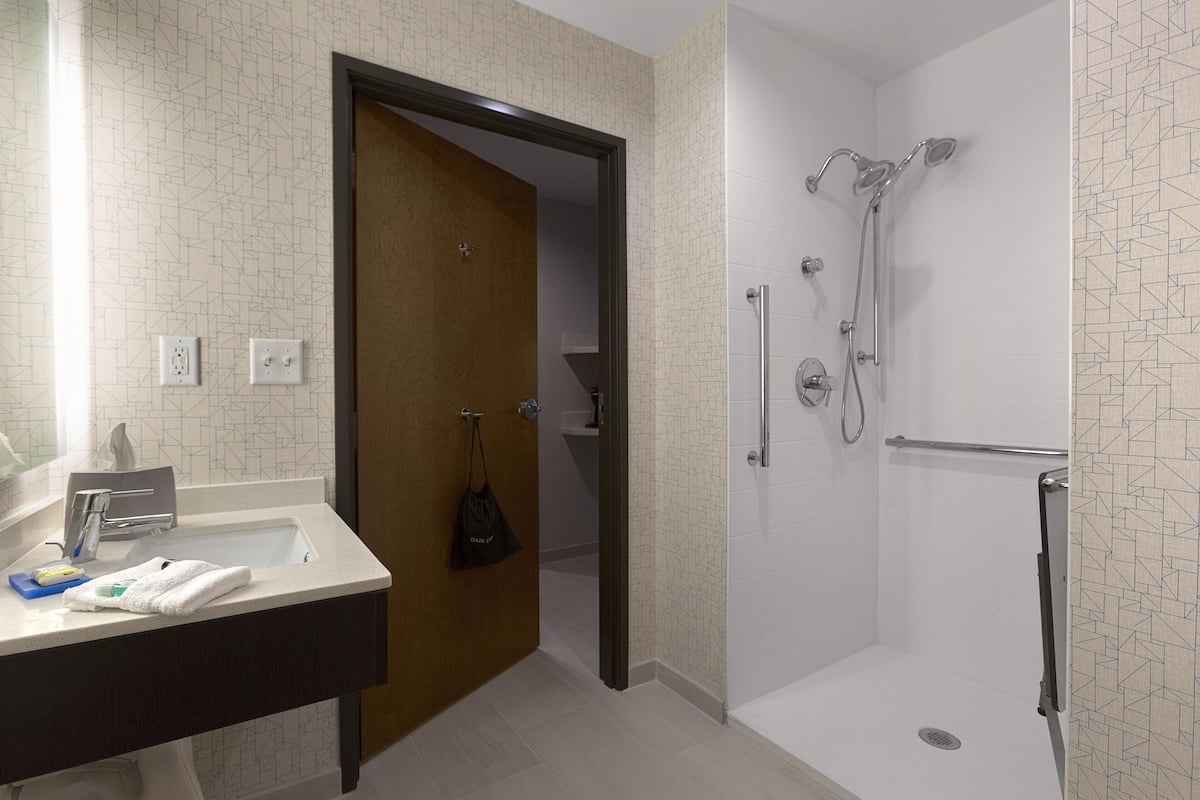 A bathroom with a shower, a sink, and a towel rack.