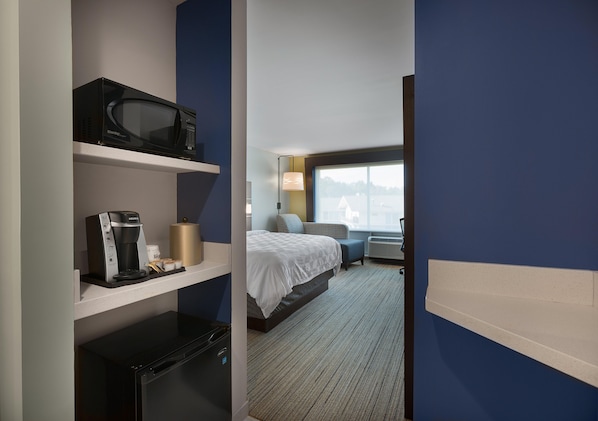 A hotel room with a bed, a microwave, a coffee maker, and a desk lamp. - Holiday Inn Express Lake Park by IHG (Lake Park)