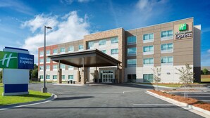 A Holiday Inn Express building with a covered entrance, a parking lot, and a landscaped area with small trees. - Holiday Inn Express Lake Park by IHG (Lake Park)