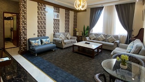 A modern living room with a sofa set, a coffee table, and a glass table with flowers. - Aral Hotel (Tabuk)