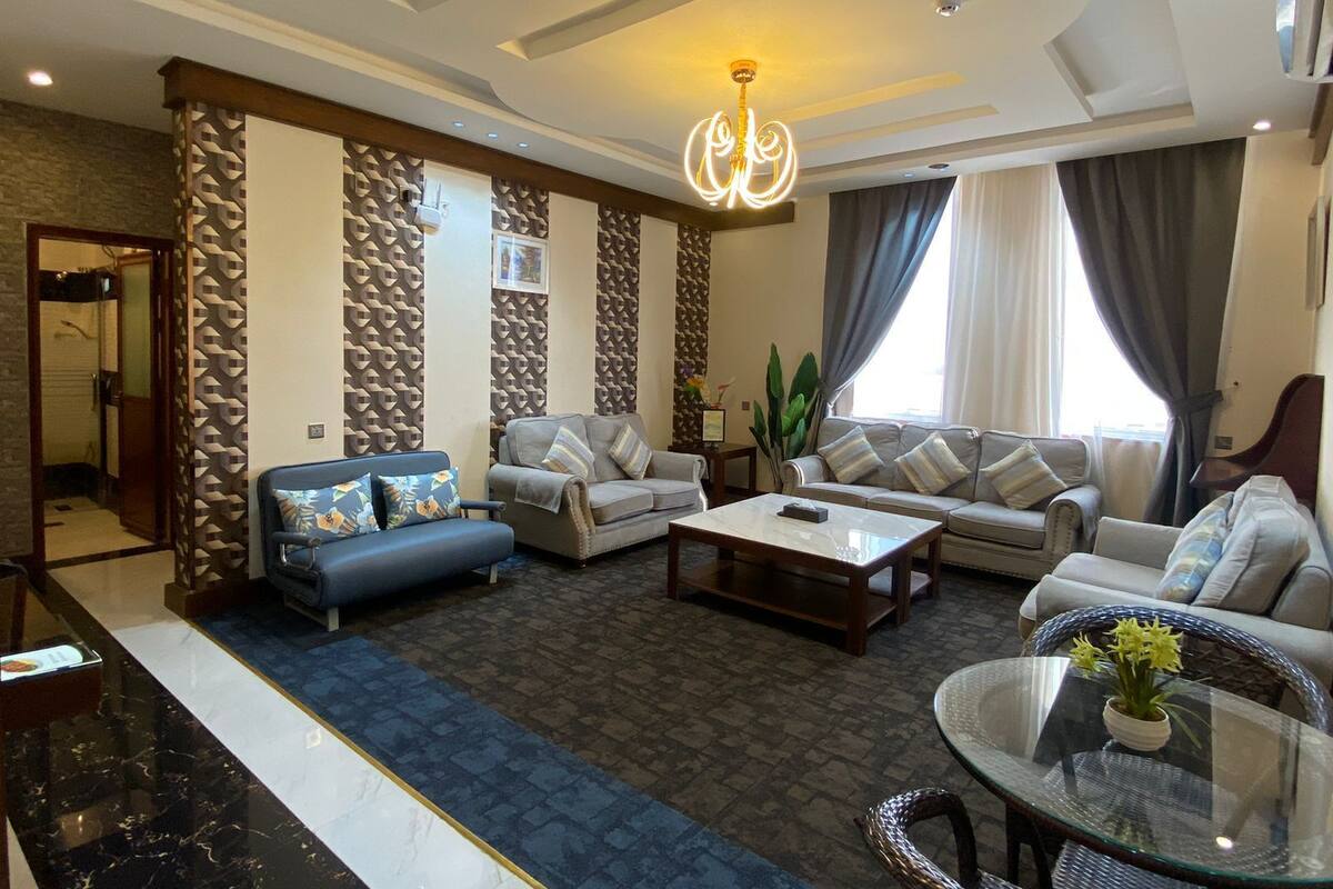 A modern living room with a sofa set, a coffee table, and a glass table with flowers.
