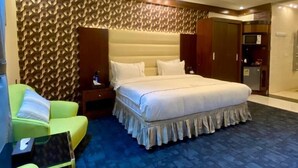 A hotel room with a large bed, a green sofa, a small table, and a patterned carpet. - Aral Hotel (Tabuk)