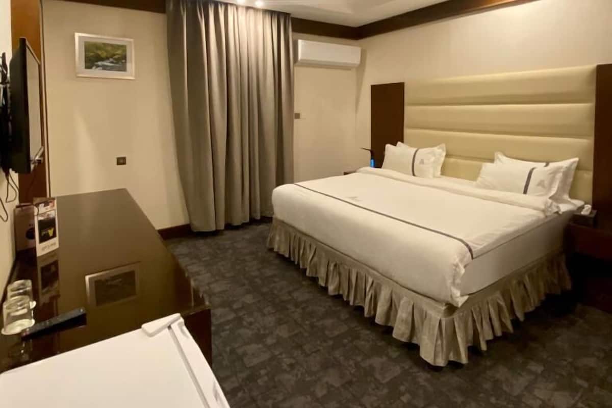 A hotel room with a large bed, a desk, and a mirror.