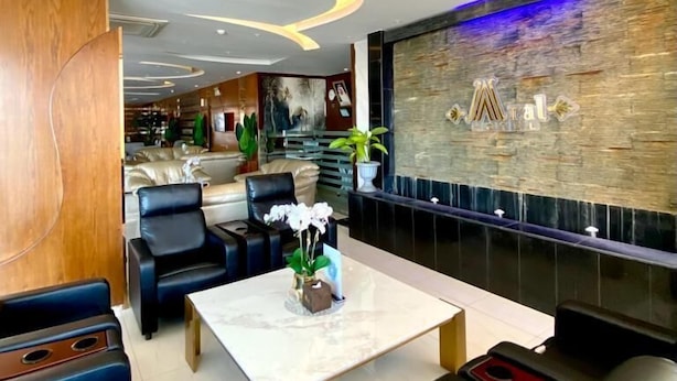 A modern hotel lobby with a marble coffee table, leather seating, a stone accent wall, and a reception area in the background. - Aral Hotel (Tabuk)