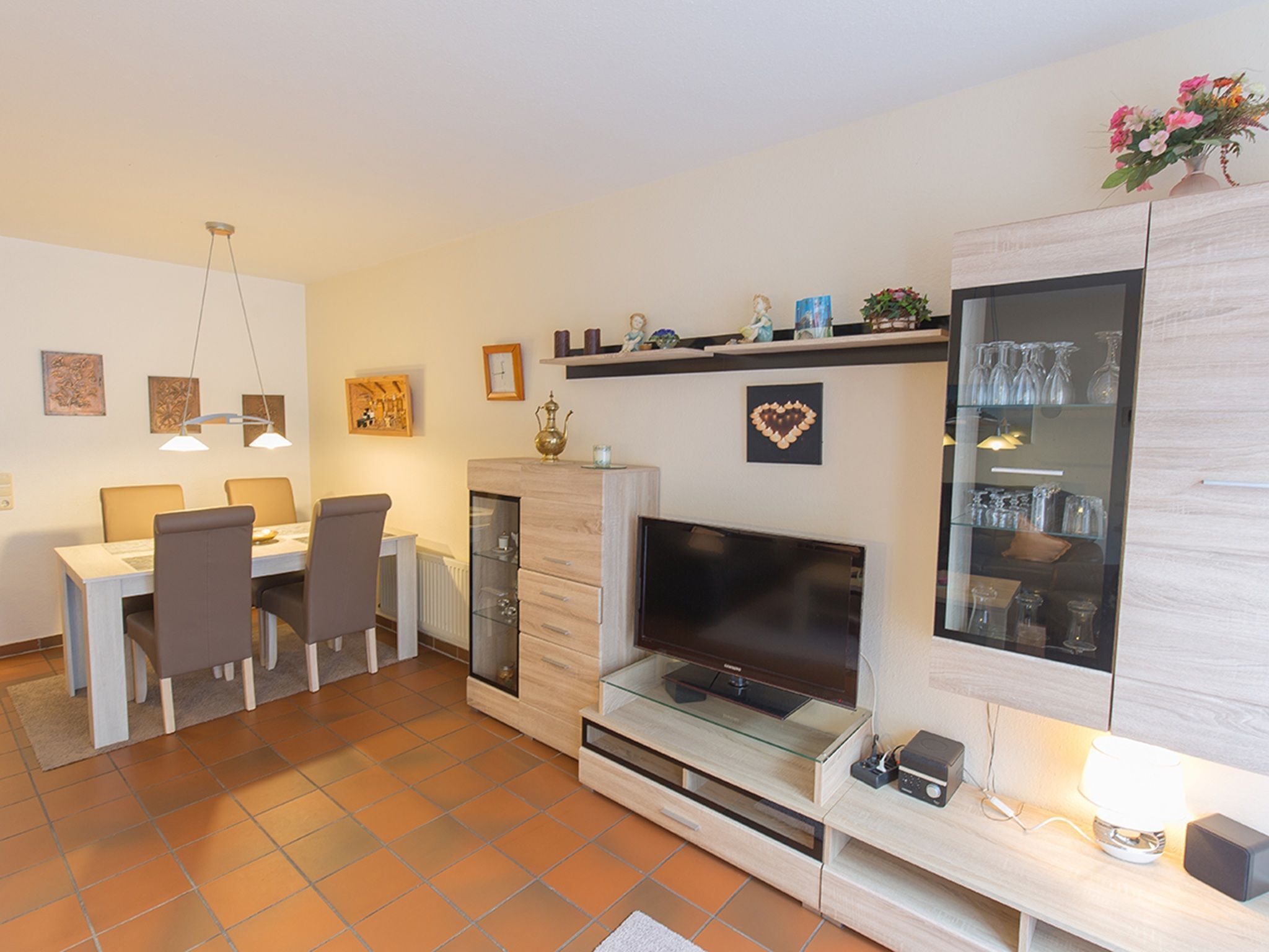A modern living room with a TV, dining table, chairs, and a fireplace.