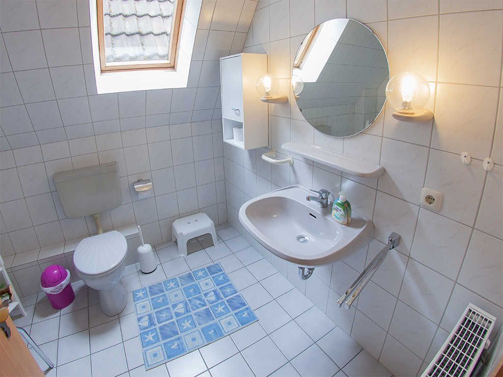 Une salle de bain équipée de toilettes, d’un lavabo, d’un miroir et d’une fenêtre.