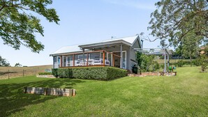 Ein Haus mit überdachter Veranda, einem gepflegten Rasen und einem Kiesweg, der zum Eingang führt.