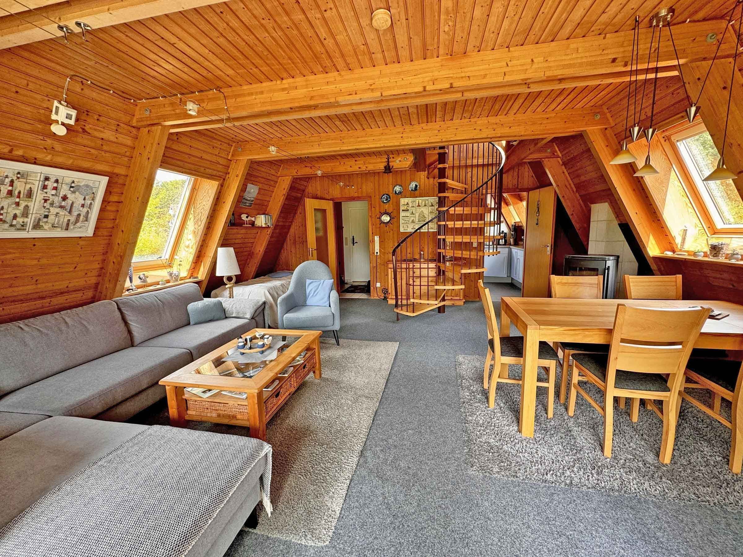 A cozy, wooden interior with a living room, dining area, and a spiral staircase.