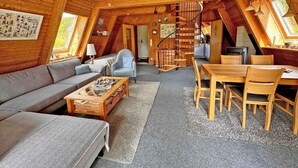 Un intérieur chaleureux, avec des éléments en bois, comprenant un salon, un coin repas et un escalier en colimaçon.
