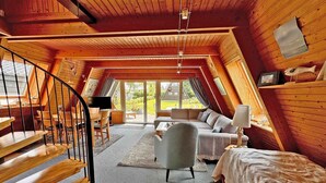 Une chambre mansardée chaleureuse avec un escalier en bois, un canapé, un fauteuil et un lit.