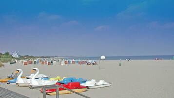 A beach with several small boats and a lifeguard tower in the background.