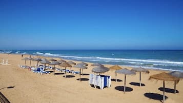 In Strandnähe, weißer Sandstrand, Liegestühle, Sonnenschirme