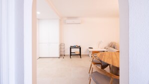 Un salon minimaliste comprenant un coin repas, des murs blancs et un sol carrelé.