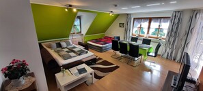 A modern living room with a sofa, a dining table, and a TV.