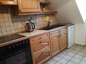 A kitchen with wooden cabinets, a stove, a dishwasher, and a tiled backsplash.