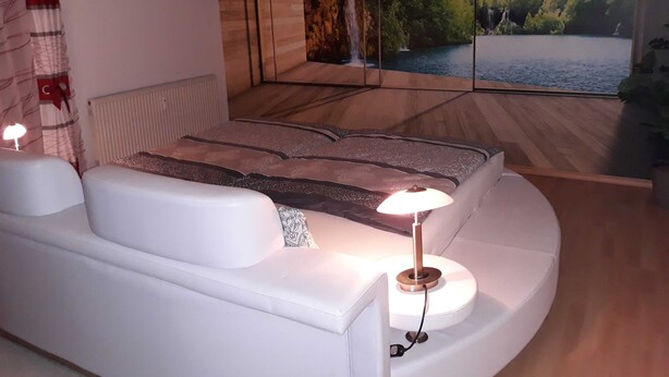 Un dormitorio moderno con una cama grande, una mesita de noche, una lámpara y un ventanal con vistas panorámicas.