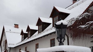 Una hilera de casas de madera tradicionales con tejados cubiertos de nieve y un farol.