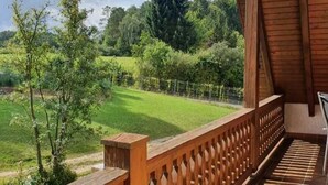 Un balcón de madera con vistas a un campo verde y árboles.
