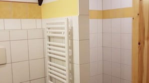 Une salle de bain avec des carreaux blancs, un porte-serviettes blanc et une porte en bois.