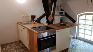 Une cuisine de taille réduite équipée d’un évier, d’une cuisinière, d’un four et d’un four à micro-ondes.