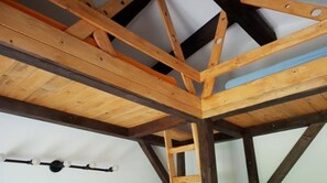 Eine Holzbalkendecke mit sichtbaren Trägern und einer hängenden Leuchte.