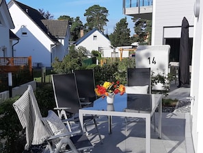 Un espace extérieur aménagé avec une table et des chaises, un pot de fleurs et un panneau portant le numéro « 14 ».