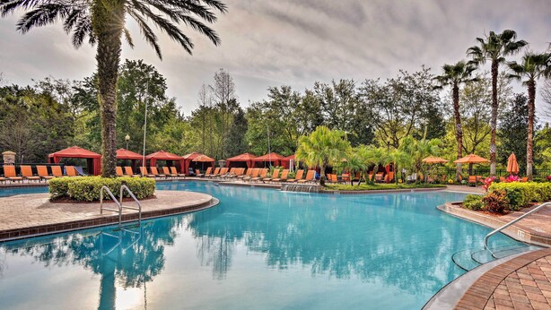 A swimming pool with lounge chairs and umbrellas, surrounded by palm trees and greenery. - 10 Mi to Disney: Davenport Condo w/ Pool Access! (Davenport)