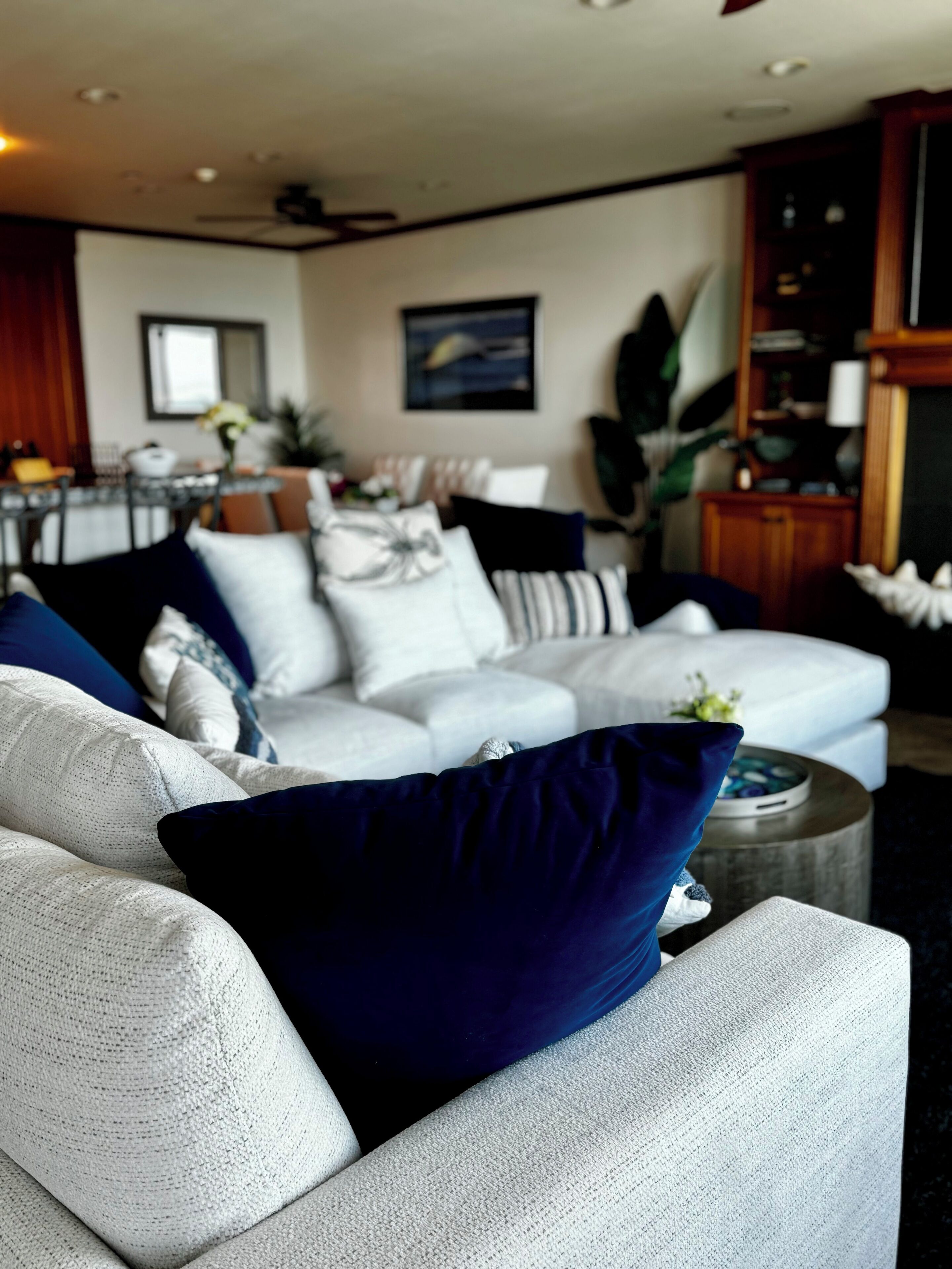 Un salon moderne avec un canapé blanc, des coussins bleus et blancs, et une table basse ronde.