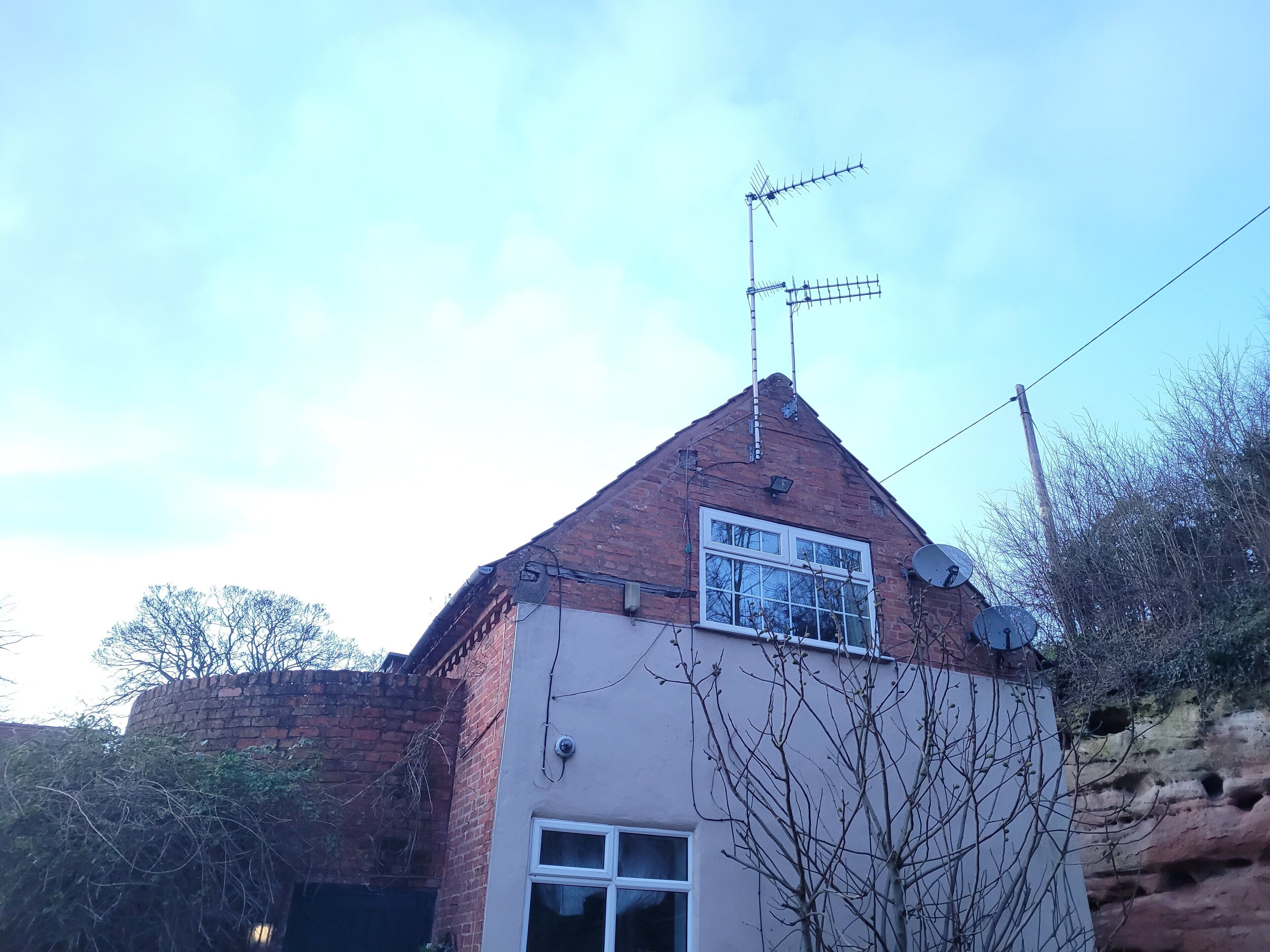 A house with a brick exterior, a pitched roof, and a satellite dish.