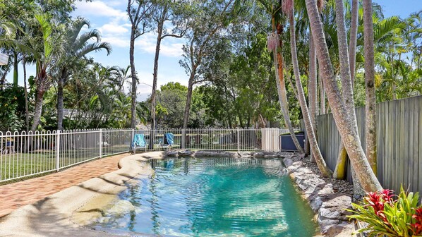 A swimming pool with clear water, surrounded by a white fence and various trees. - Clouds End - Walking Distance to Noosa River, Shops & Restaurants (Noosaville)