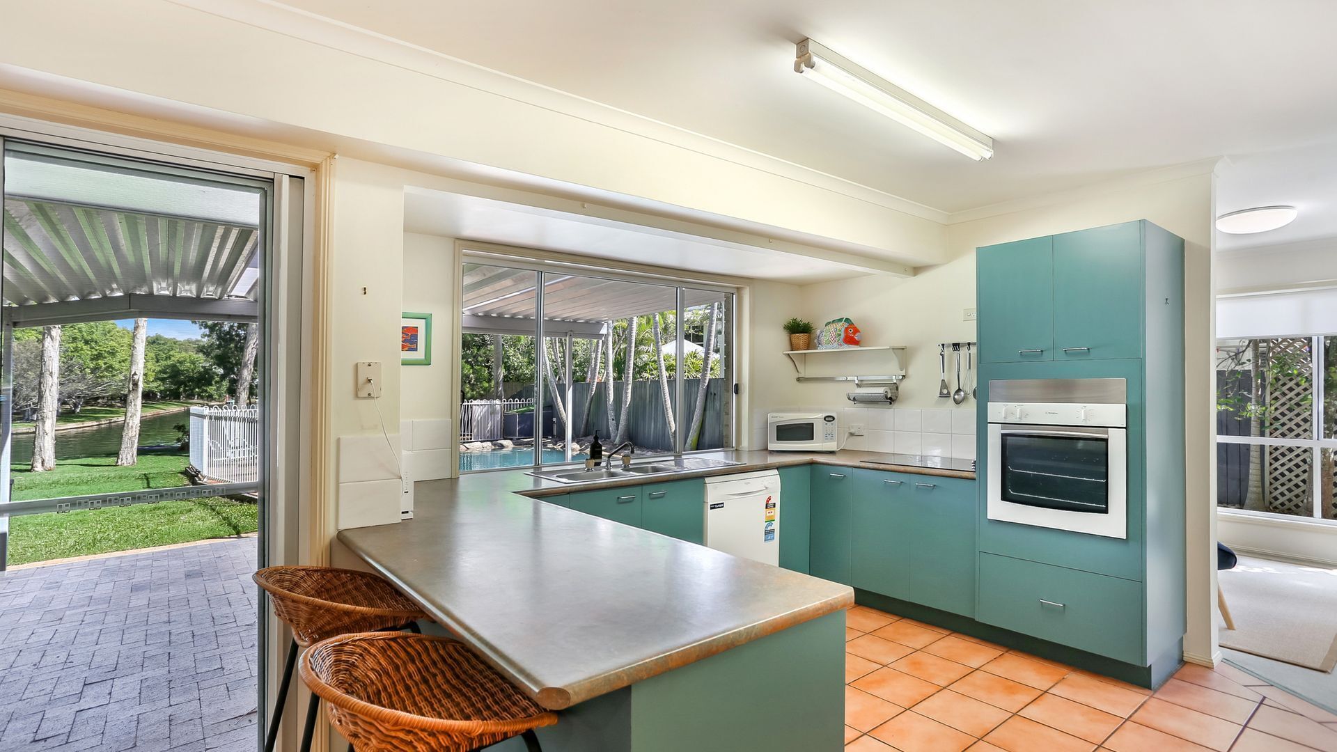 A modern kitchen with a large island, built-in appliances, and a view of a backyard.