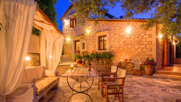 Une terrasse extérieure avec un sol en pierre, une table entourée de chaises et des plantes en pot.