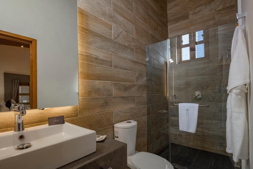 A modern bathroom with a large sink, toilet, and glass-enclosed shower.