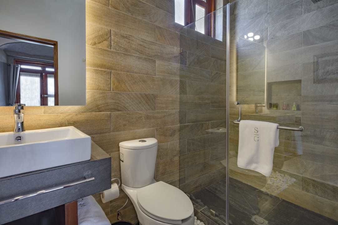 Uma casa de banho moderna com lavatório, sanita e zona de duche com parede de vidro.