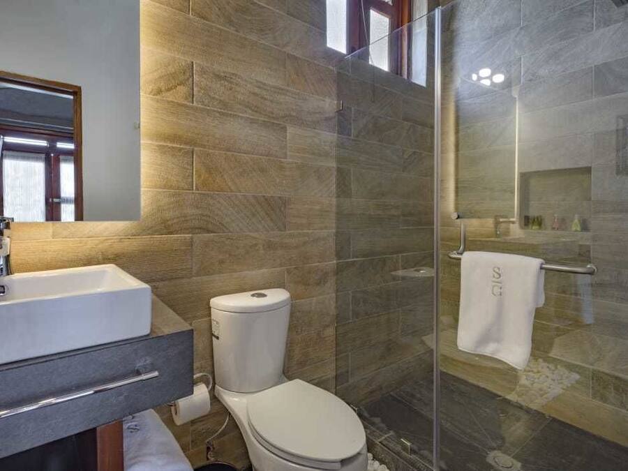 Uma casa de banho moderna com lavatório, sanita e zona de duche com parede de vidro.