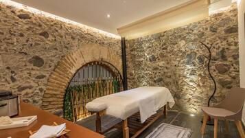 Relax in a serene space with a massage table, stone archway, and balcony access.