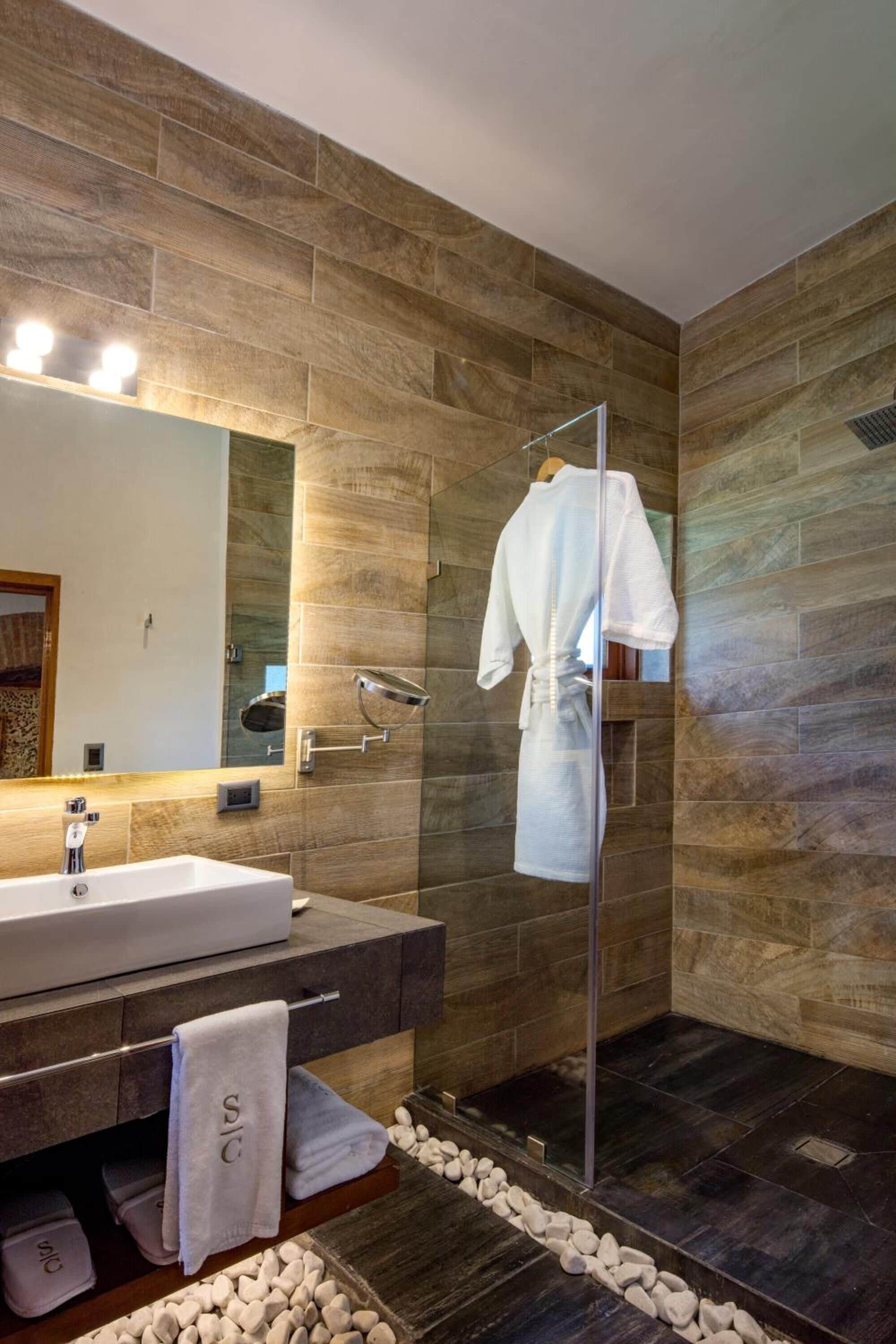 A modern bathroom with a large mirror, a white bathtub, and a glass shower enclosure.