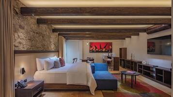 Una habitación de hotel moderna con una cama grande, un sofá, un televisor y un escritorio.