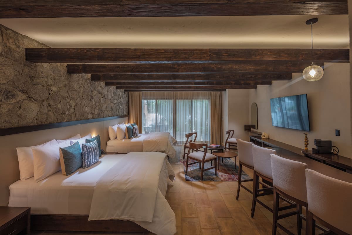 A hotel room with a large bed, a desk, and a TV mounted on the wall.