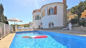 A swimming pool with lounge chairs and a building with arched windows. - AMIBARCO-Gran Vista-Wifi y Parking Gratis. (Calpe)