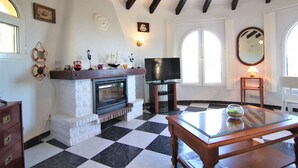 A living room with a fireplace, a television, and a checkered floor. - AMIBARCO-Gran Vista-Wifi y Parking Gratis. (Calpe)